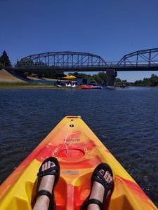image of kayak on river with bridge in the background