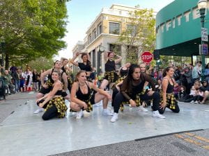Kelsey striking a pose with a group of dancers dressed in black with yellow flannels on a street in santa cruz.